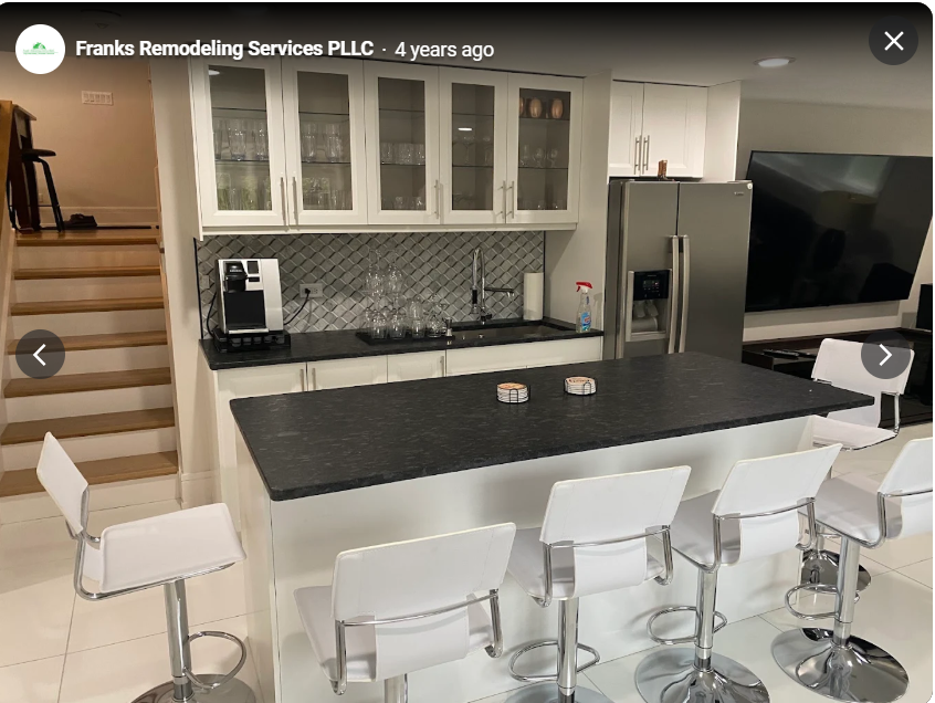 Open kitchen with a dark island countertop and white bar stools